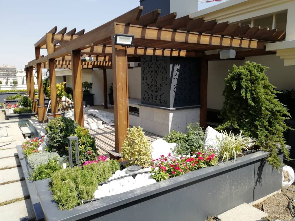A modern garden space featuring a wooden pergola, lush greenery, and colorful flowers, designed for relaxation and outdoor living.