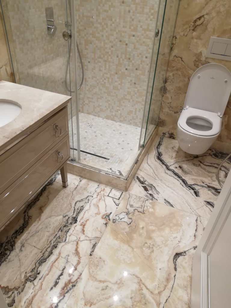Modern bathroom renovation featuring marble flooring, sleek vanity, glass shower, and contemporary design.