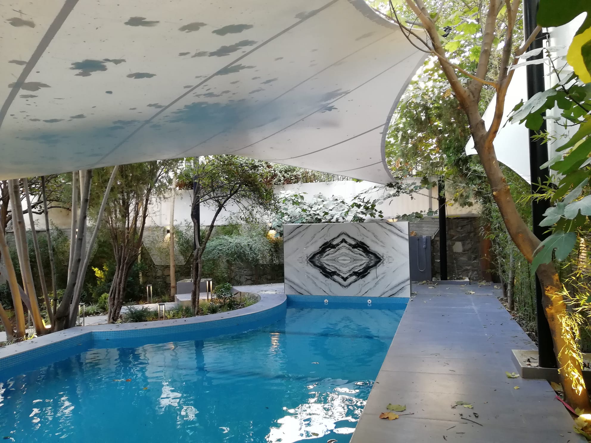 Before and after outdoor swimming pool construction showing the transformation from raw concrete structure to a finished modern pool with landscaping.