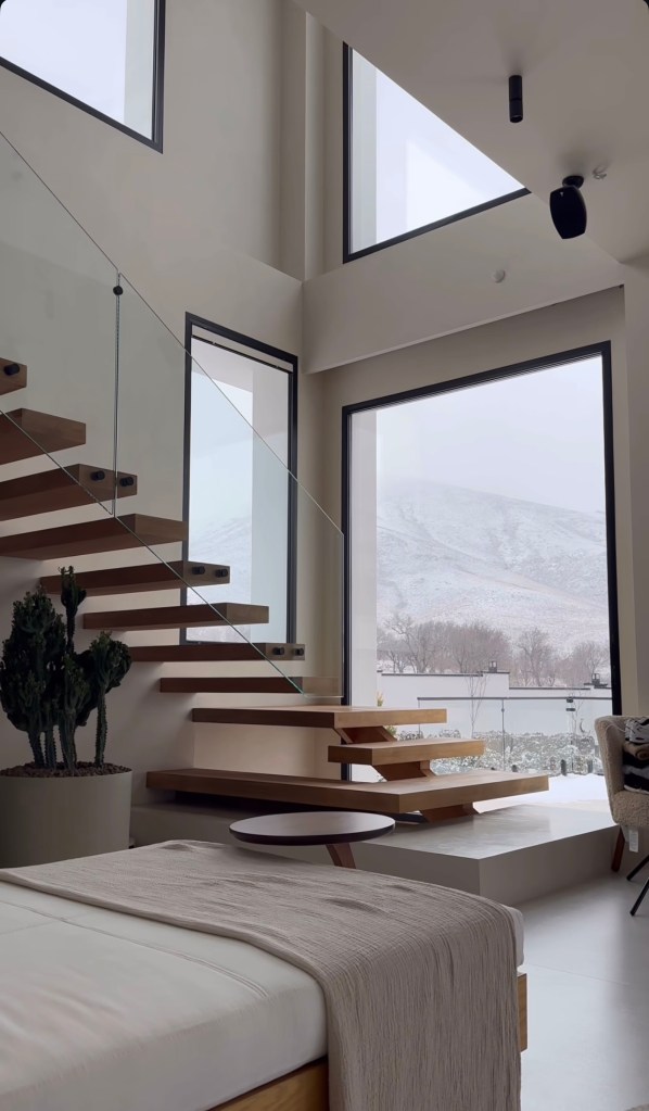 Modern floating wooden staircase with glass railing, minimalist design, and natural light in a renovated home.
