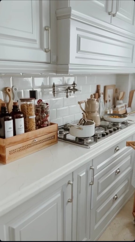 Classic kitchen renovation with white cabinets, marble countertop, gas stove, and modern accessories in the Netherlands