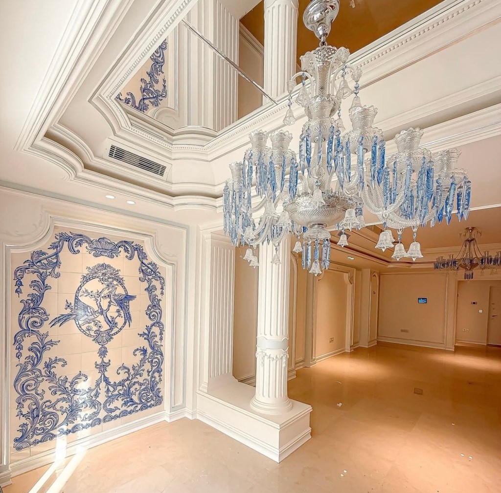 interior with blue crystal chandelier, white decorative columns, and artistic wall mural
