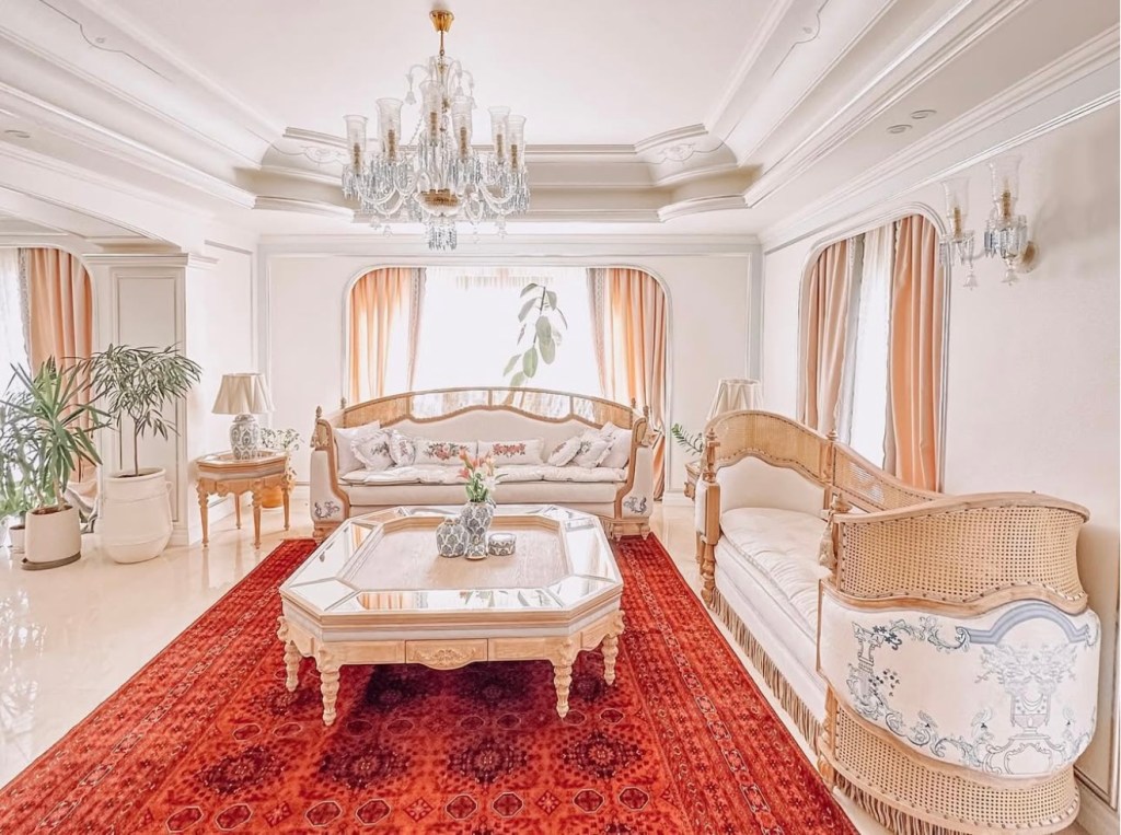 Bright living room with chandelier, vintage sofas, and red Persian rug
