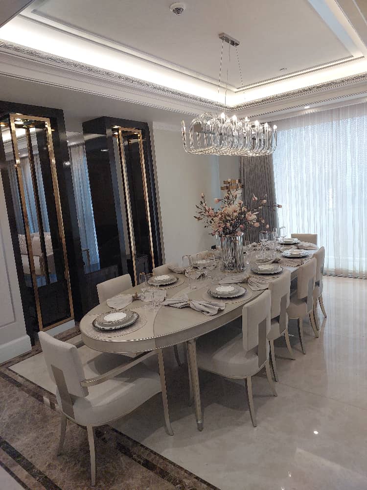 Luxury dining room design featuring a large oval table, plush chairs, elegant chandelier, and stylish modern decor.
