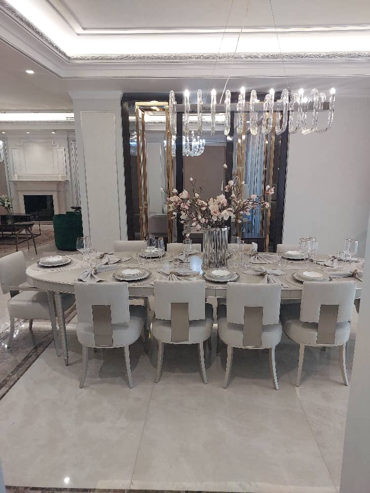 Modern dining room setup with a rectangular table, elegant chairs, decorative chandelier, and sophisticated interior design.