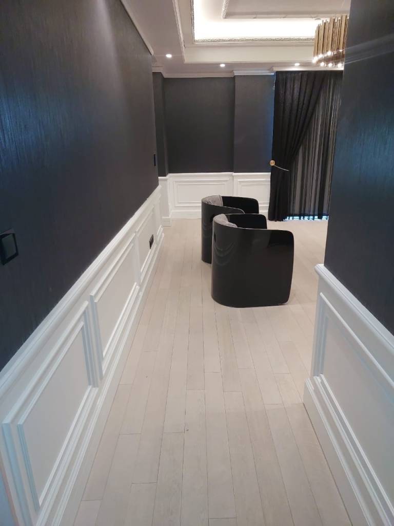 Minimalist office corridor design with modern wall panels, light flooring, and contemporary seating area.