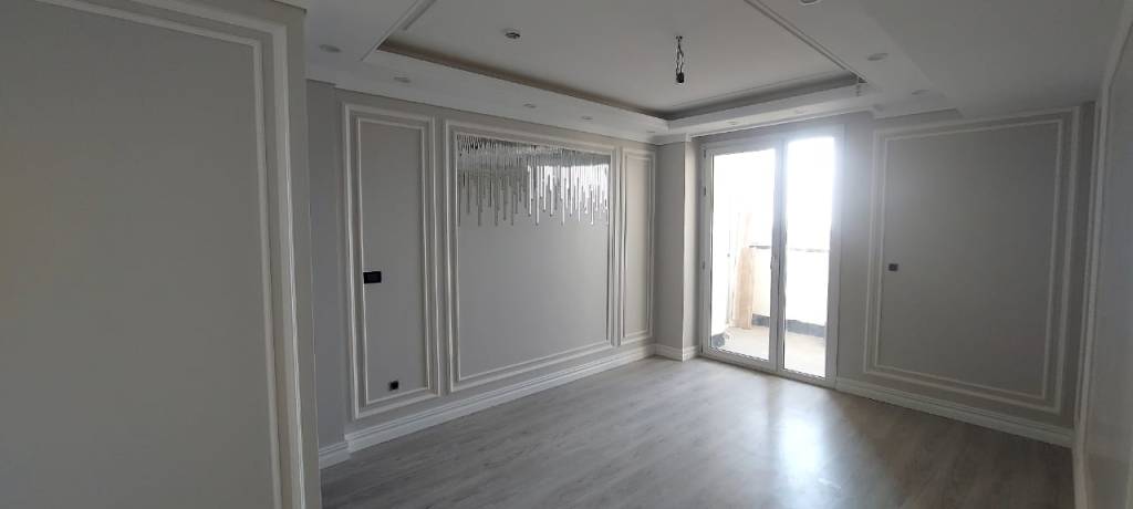 Minimalist bedroom with decorative wall molding, balcony door, and chandelier accent lighting