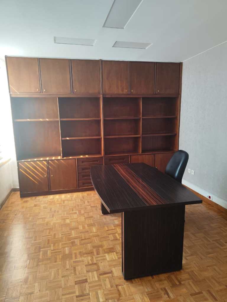 Classic office renovation with wooden desk, built-in bookshelf, and natural lighting for a professional workspace.
