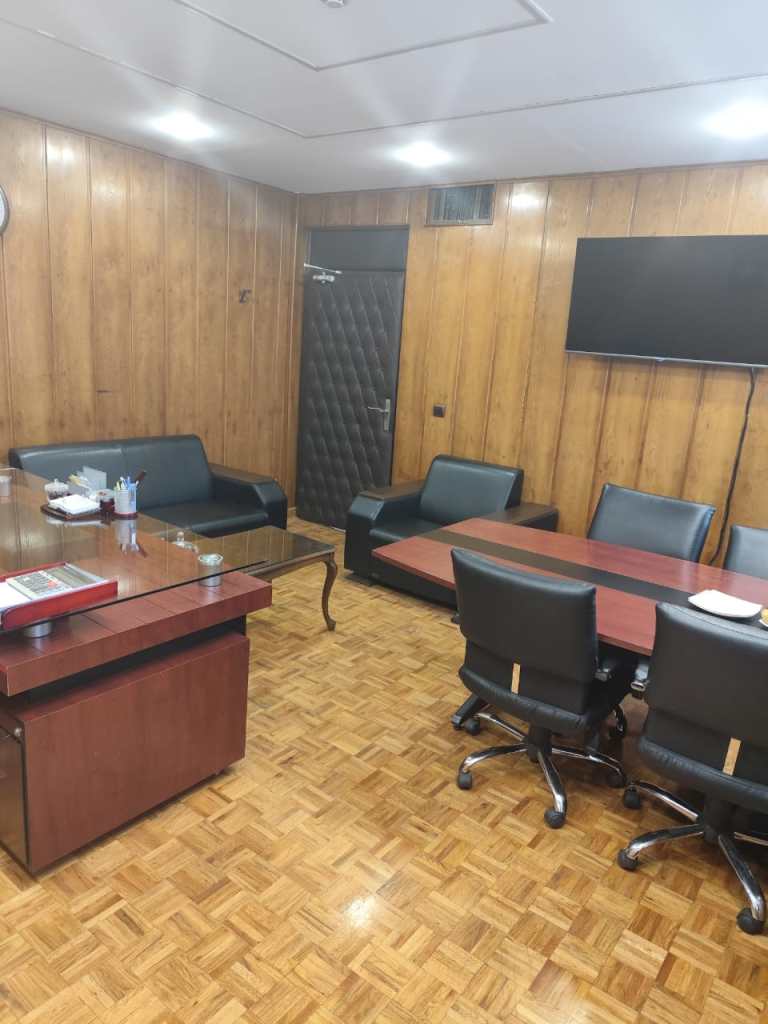 Renovated office meeting room with black leather chairs, wooden conference table, and polished wood panel walls.