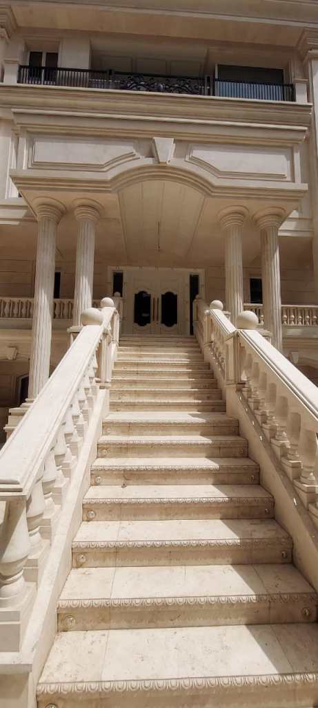 Luxury stone staircase with classic white railings and decorative details, showcasing elegant architectural design.