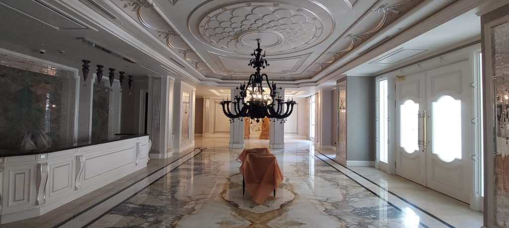 Luxury lobby interior with marble flooring, decorative columns, and elegant chandeliers
